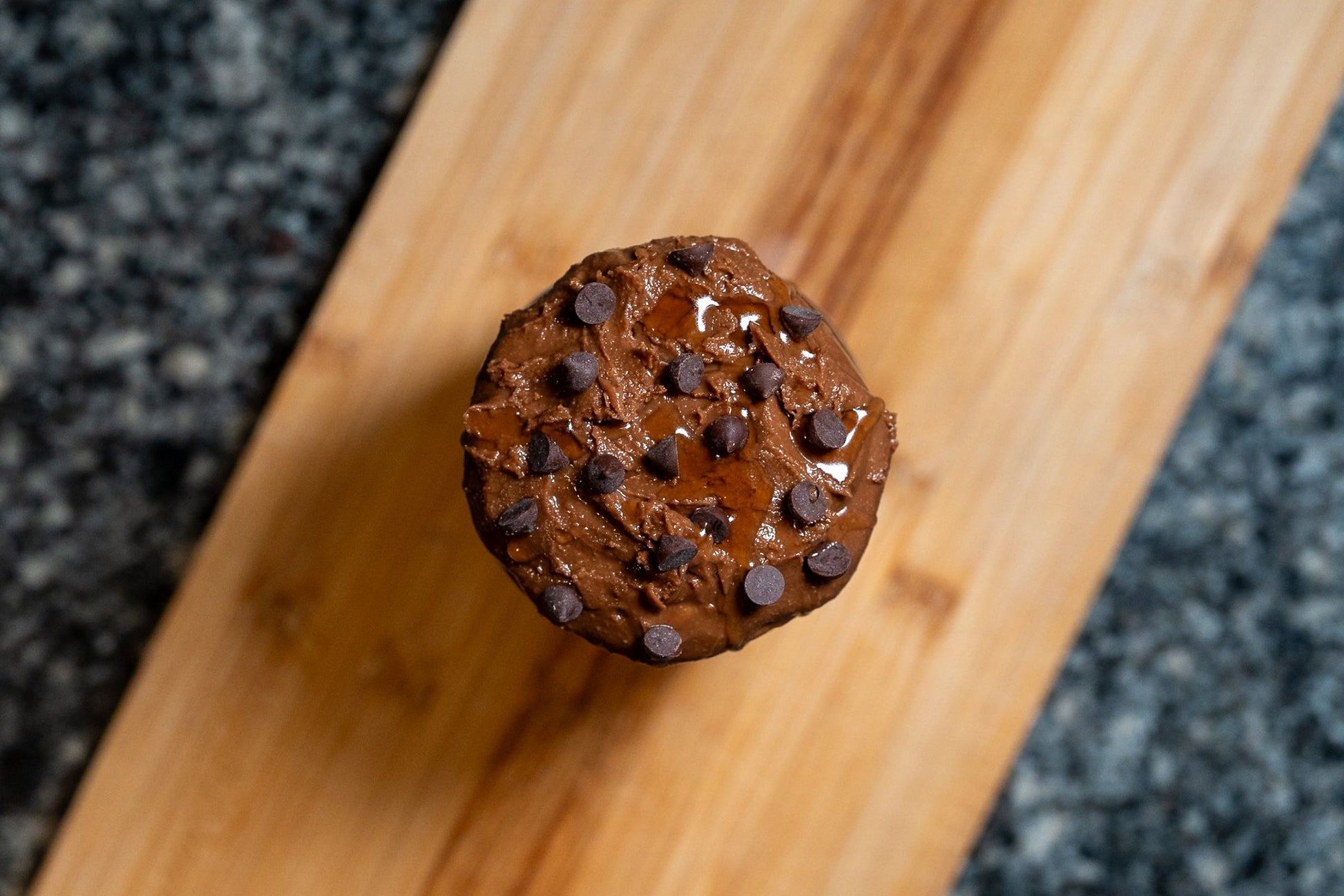Overhead shot of cacao & agave peanut butter jar with chocolate chips on a wooden block