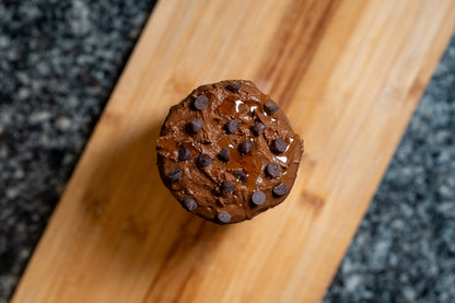 Overhead shot of cacao & agave peanut butter jar with chocolate chips on a wooden block