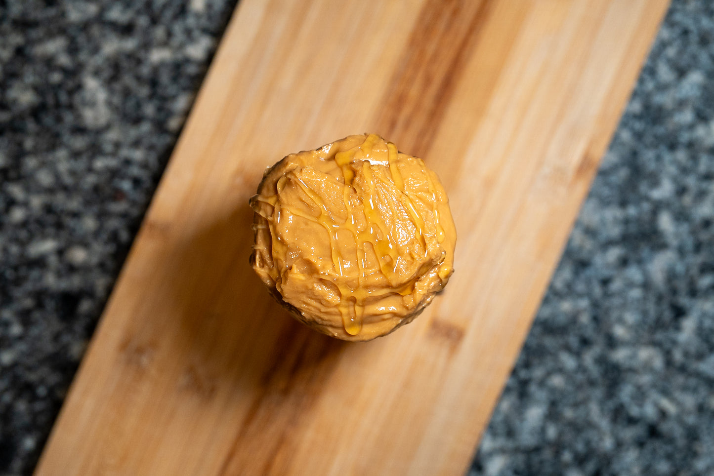 Overhead photo of Texas honey peanut butter on a wooden surface with a dark textured background